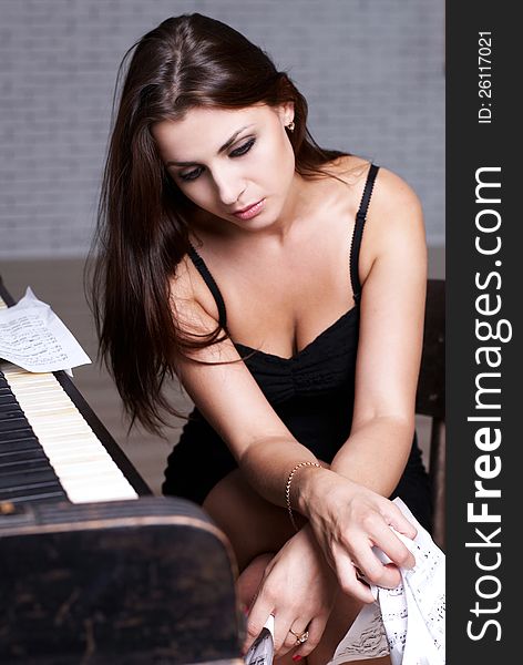 Sad girl near piano with crumpled paper with music notes everywhere