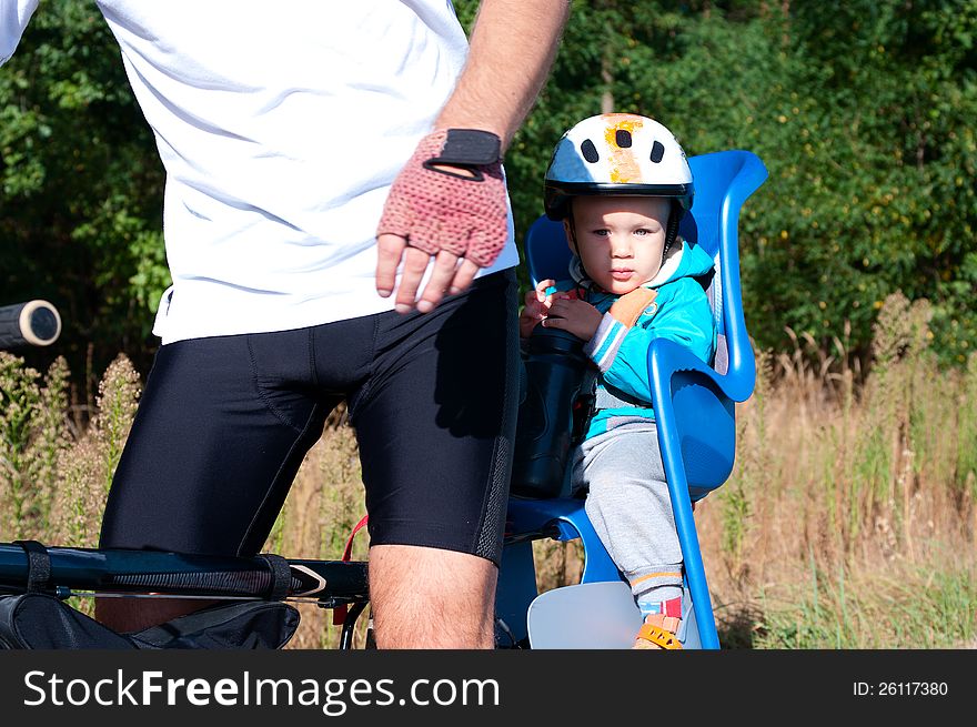 Little boy in bike child seat outdoors behind his dad