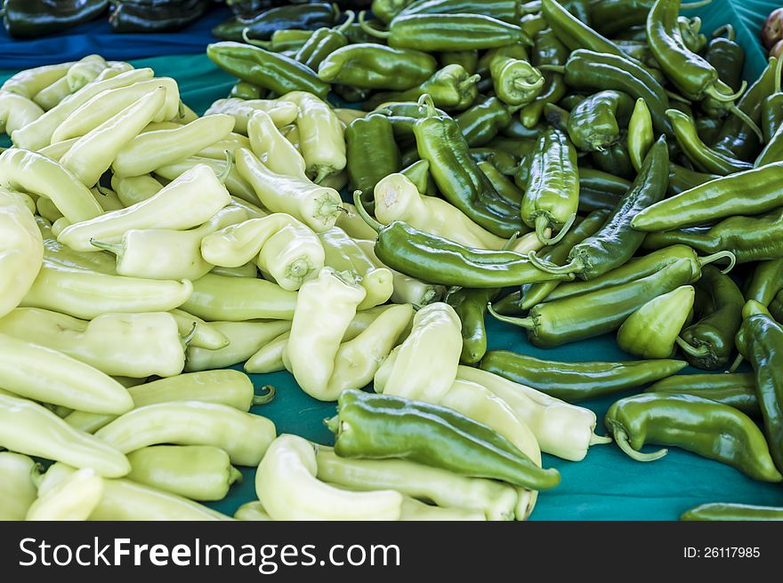 Pile of green chili peppers on a table for sale. Pile of green chili peppers on a table for sale.