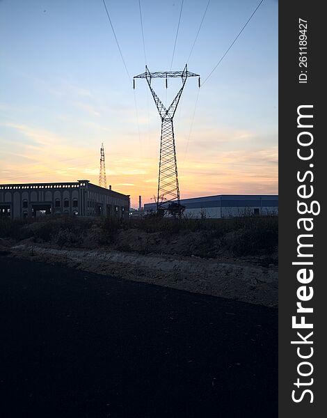 Empty road with abandoned warehouses and pylons at sunset