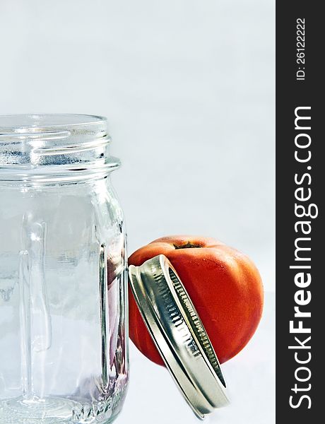 Pint jar with ring and tomato on white background. Pint jar with ring and tomato on white background