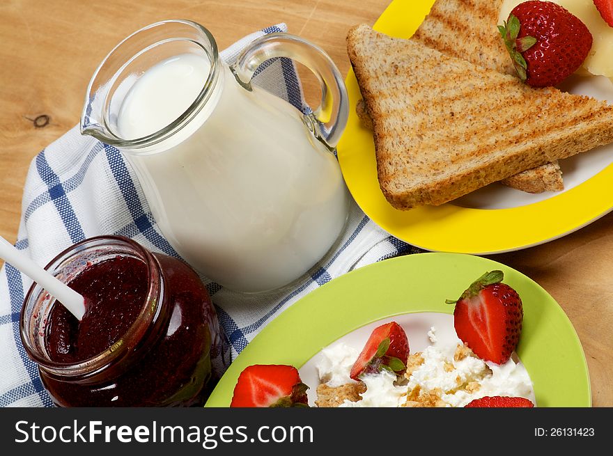 Village Breakfast of Toasts, Strawberries, Jam, Milk and Curds close up on wooden background