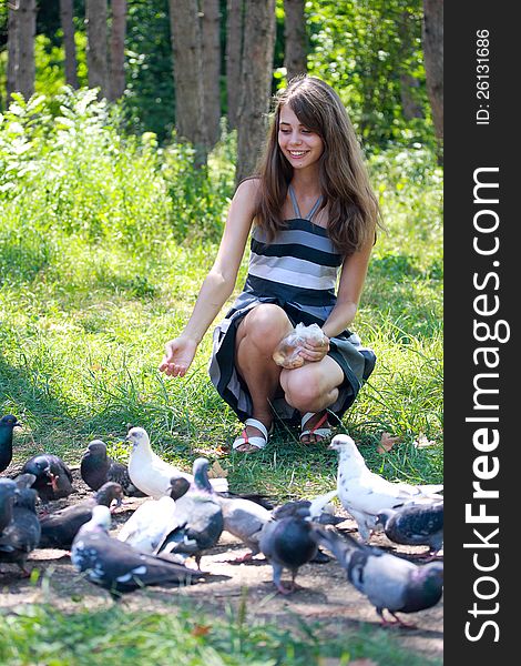 Girl in summer dress feeding pigeons in a park. Girl in summer dress feeding pigeons in a park