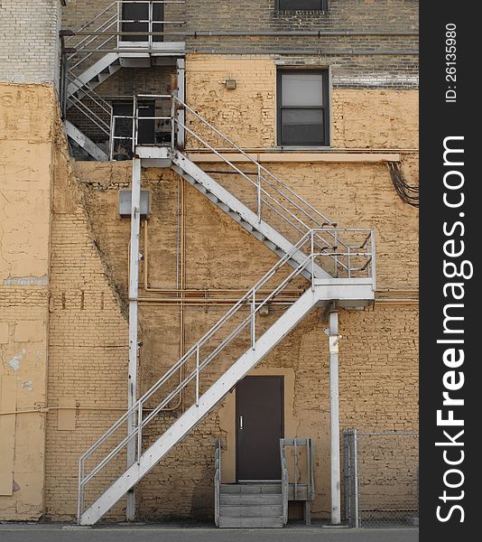 Outside metal fire escape steps on the side of an old brick building in an alley. Outside metal fire escape steps on the side of an old brick building in an alley.