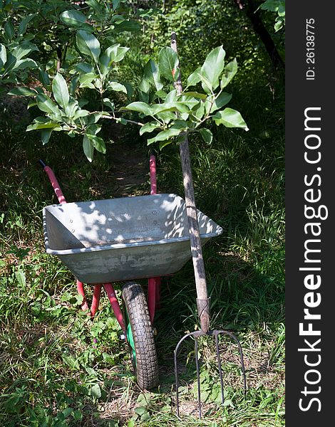 A wheelbarrow with a garden tool. A wheelbarrow with a garden tool