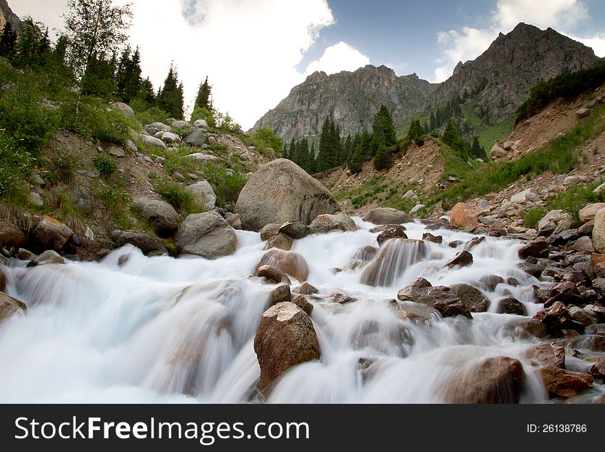 The rough mountain river flows on stones with the big speed