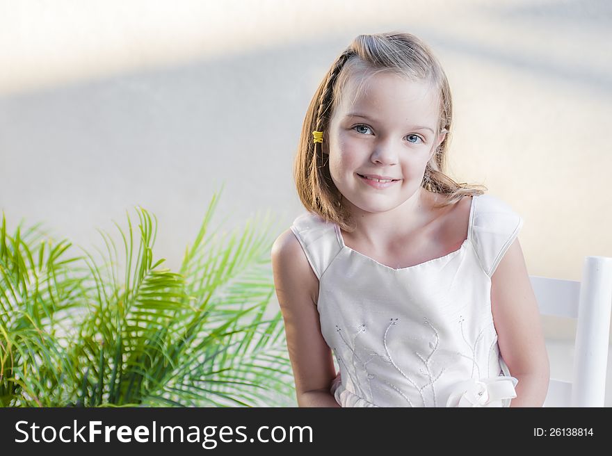 Young girl looking at the camera and posing for a picture by a plant. Young girl looking at the camera and posing for a picture by a plant.