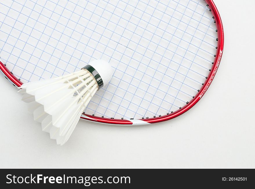 Badminton racket in red color and light blue string with shuttlecock in top right partial angle view on white background. Badminton racket in red color and light blue string with shuttlecock in top right partial angle view on white background