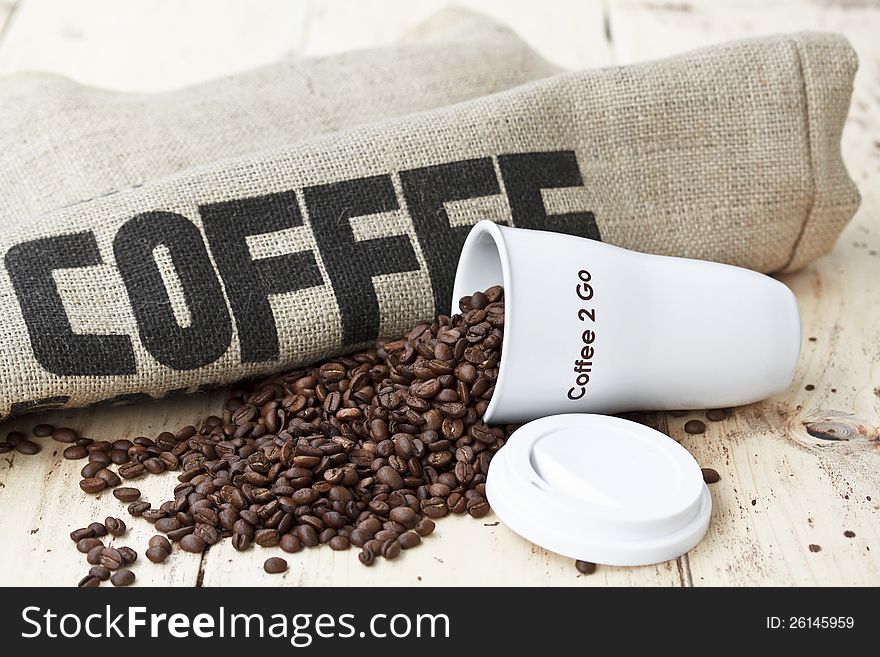 White coffee cup on jute background with Coffee beans. White coffee cup on jute background with Coffee beans