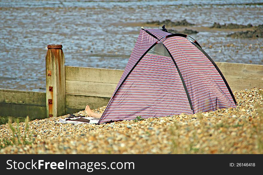 Photo of a person using a beach tent for protection against the summer sun.