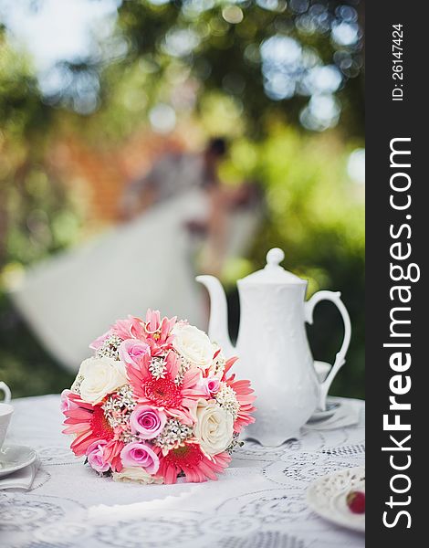 Bridal bouquet to the tea table in the background of newlyweds