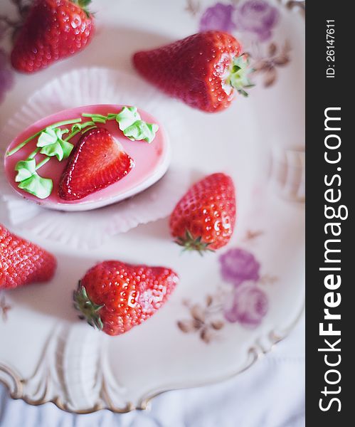 Strawberry cake on a plate surrounded by fresh strawberries