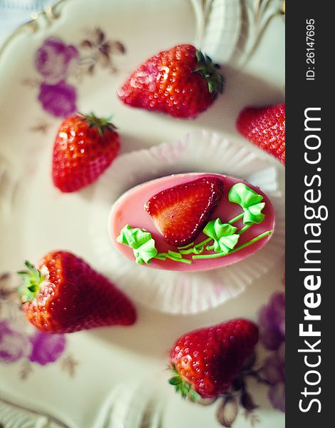 Strawberry cake on a plate surrounded by fresh strawberries