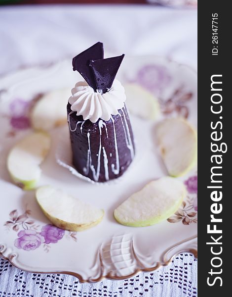 Chocolate cake on a plate surrounded by fresh pieces of apple. Chocolate cake on a plate surrounded by fresh pieces of apple