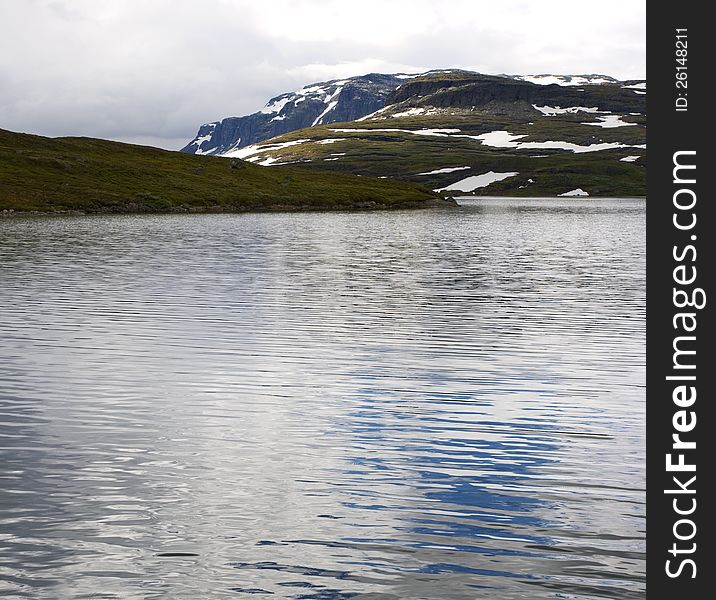 Norwegian landscape with a mountain on background and mountain lake