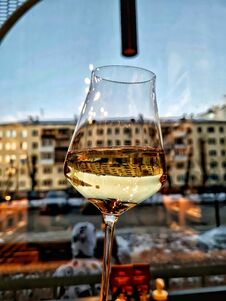 A Glass Of White Wine In Front Of A Window From A Restaurant Overlooking The City Royalty Free Stock Images