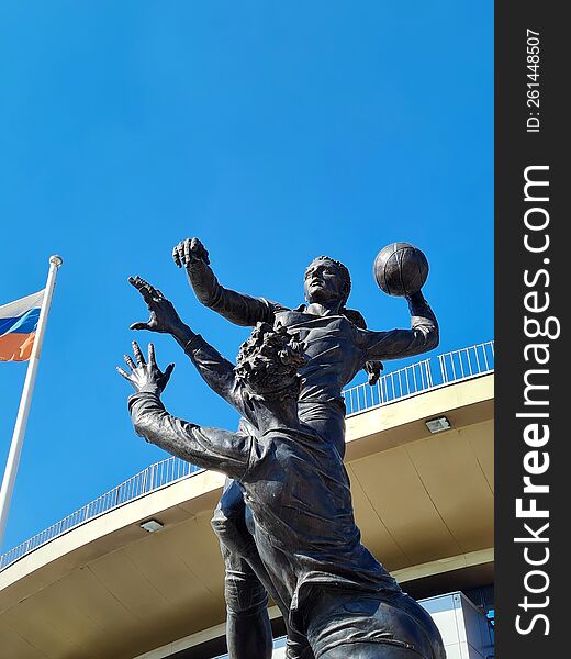 Dark Monument To Two Female Volleyball Players Under Bright Blue Sky