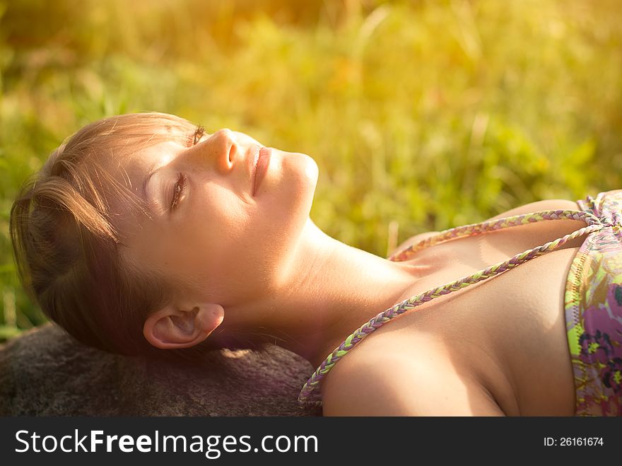 Beautiful healthy young woman lying on the stone