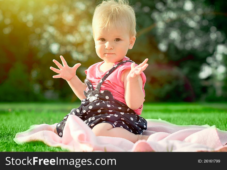 Cute playful blond 1.2 years old girl sitting on green grass outdor. Cute playful blond 1.2 years old girl sitting on green grass outdor