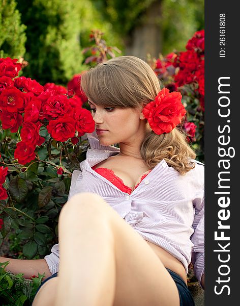 Beautiful sexy young woman in flower garden smelling red roses. Beautiful sexy young woman in flower garden smelling red roses