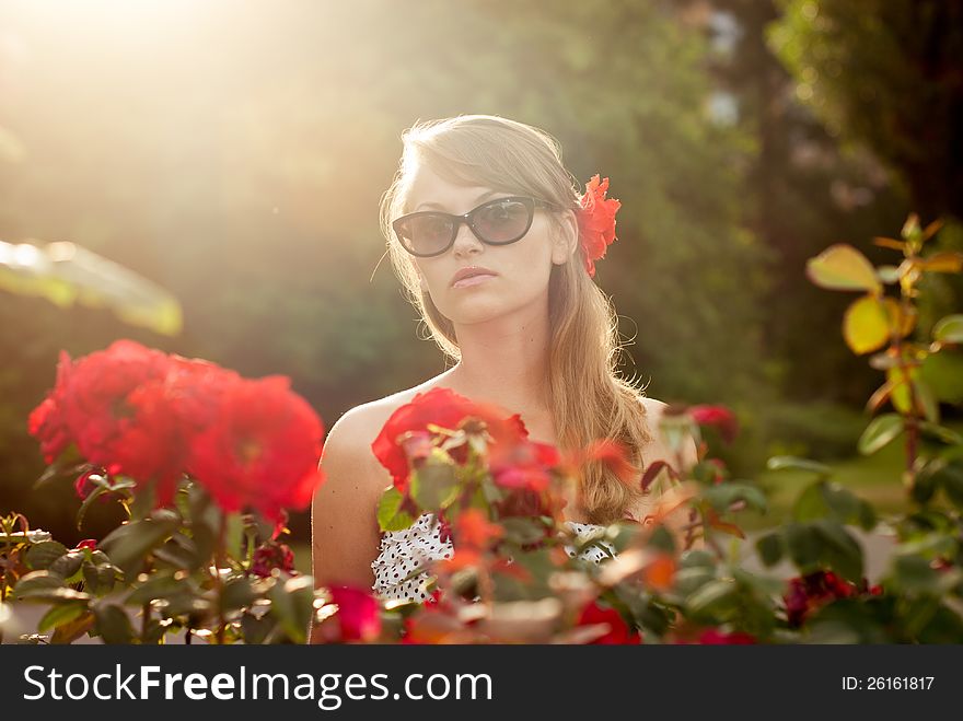 Young model in flower garden smelling red roses. Young model in flower garden smelling red roses