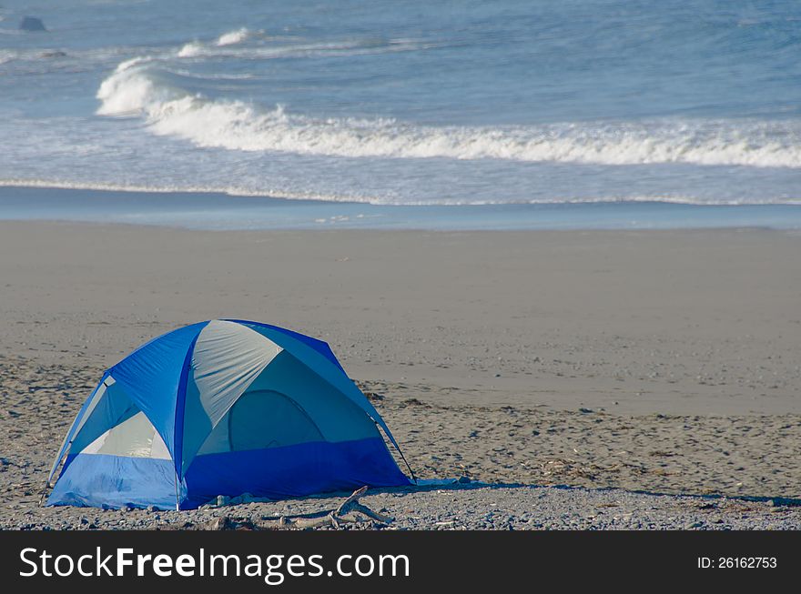 Blue nylon tent is set up on the edge of the ocean. Blue nylon tent is set up on the edge of the ocean.