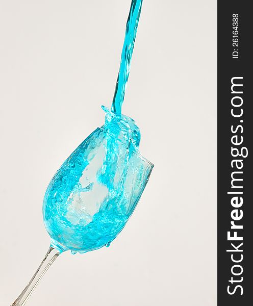 Blue water splashing out of a wine glass. Blue water splashing out of a wine glass