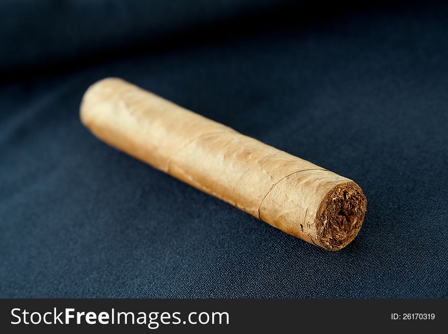 Big and flavorful cigar lying on a black fabric background. Big and flavorful cigar lying on a black fabric background
