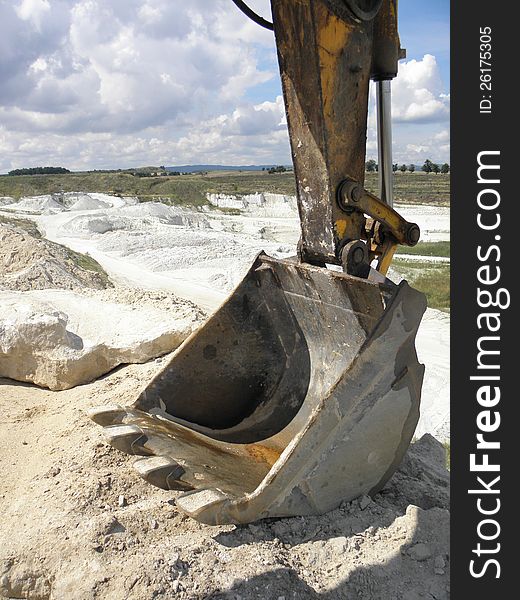 Bucket of hydraulic excavator on top of the dump in the kaolin mine