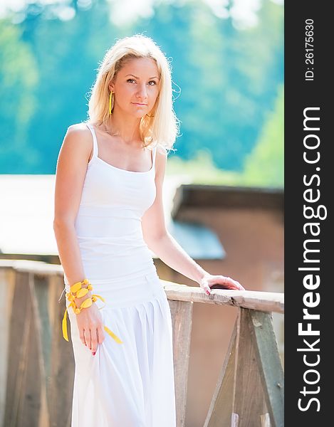 Young slim woman in white at the railing