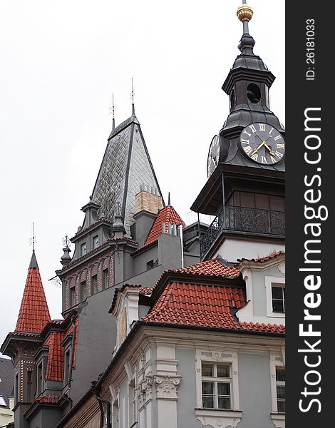 Classical Prague architecture. Gray gothic house with red tiling roof and clock tower, Czech Republic