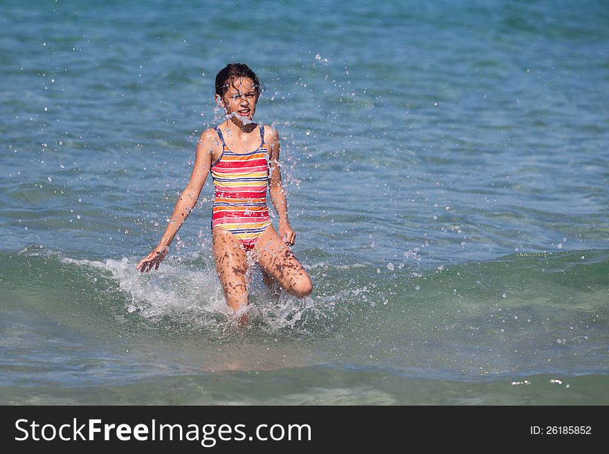 Cute young girl walks through a wave