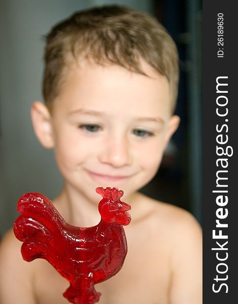 Red rooster-shaped candy in a kid's hands. Red rooster-shaped candy in a kid's hands