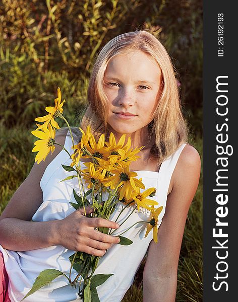 Portrait of a beautiful blonde girl with yellow flowers at summer garden. Portrait of a beautiful blonde girl with yellow flowers at summer garden