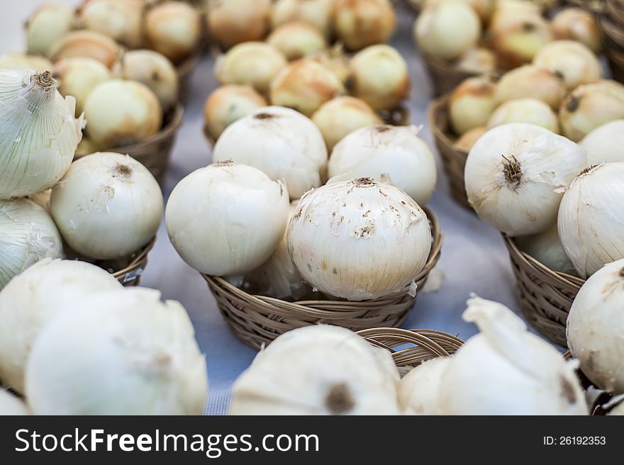 White and yellow onions organized into baskets on a table.