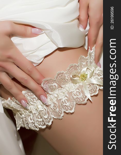Putting on a white lace bridal garter on a leg. Putting on a white lace bridal garter on a leg.