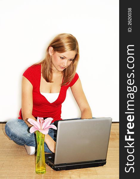 A young beautiful girl is working with her laptop and a flower. A young beautiful girl is working with her laptop and a flower