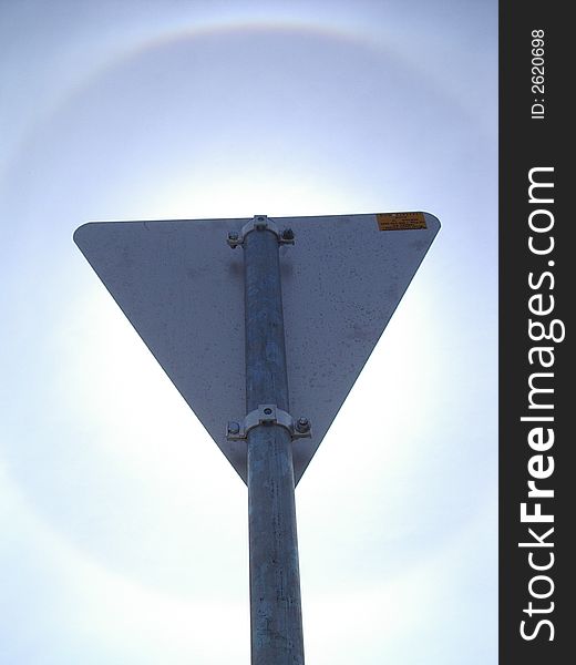 The rainbow ring around the sun as visible behind the triangle sign post. The rainbow ring around the sun as visible behind the triangle sign post