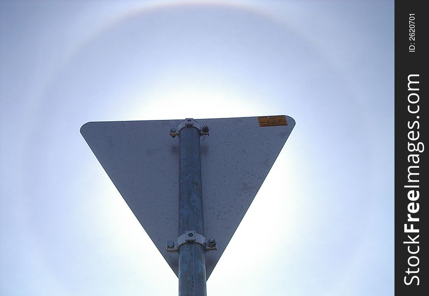 The rainbow ring around the sun as visible behind the triangle sign post. The rainbow ring around the sun as visible behind the triangle sign post