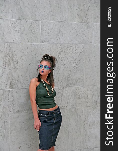 A young dark makeup model posing against wall. A young dark makeup model posing against wall