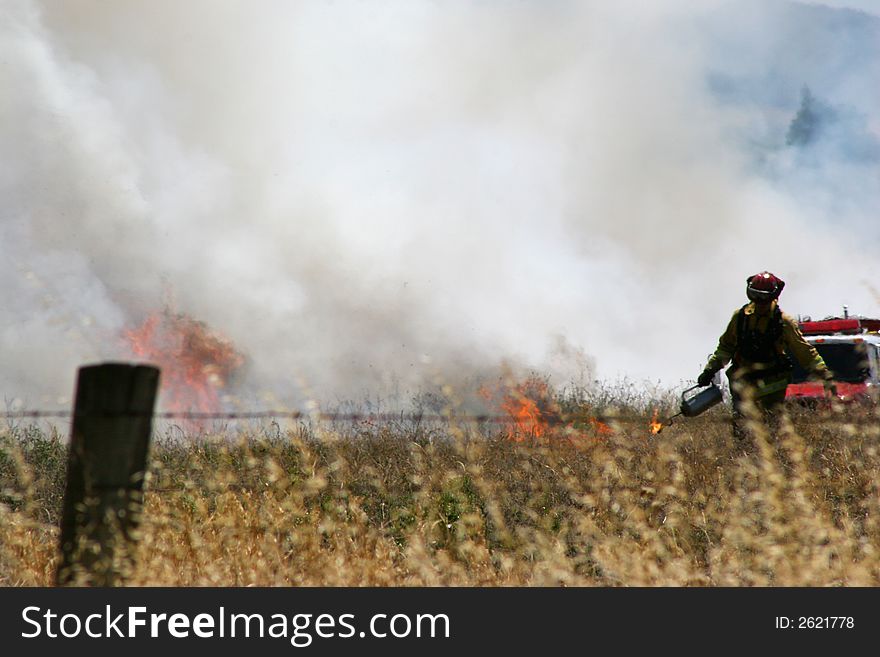 Fireman at work, lighting up some dry grass