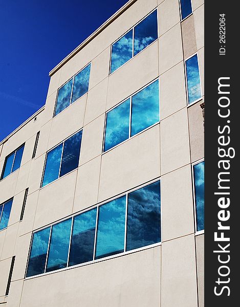 New building with blue sky background, reflected in windows