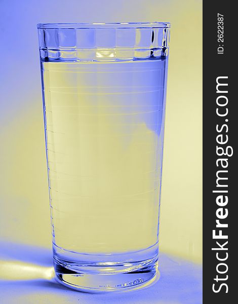 A glass of water with a blue and yellow light on the background. A glass of water with a blue and yellow light on the background.