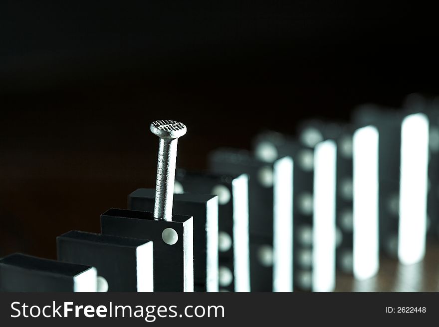 Nail and row of dominoes on a table, (studio, halogen light and flash). Nail and row of dominoes on a table, (studio, halogen light and flash).