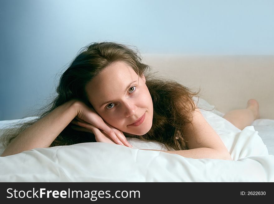 Portrait of a young awakened smiling woman lying on a bed. Portrait of a young awakened smiling woman lying on a bed
