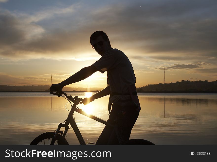 Man with bike with lake on the background. Sunset. Man with bike with lake on the background. Sunset.