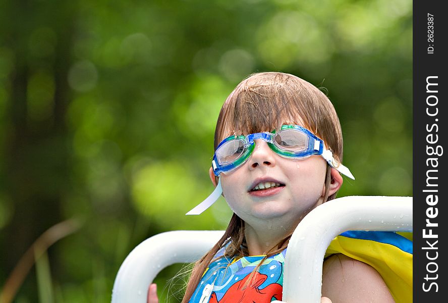 Cute small girl sitting on pool ladder wearing goggles - ears folded under straps. Cute small girl sitting on pool ladder wearing goggles - ears folded under straps.