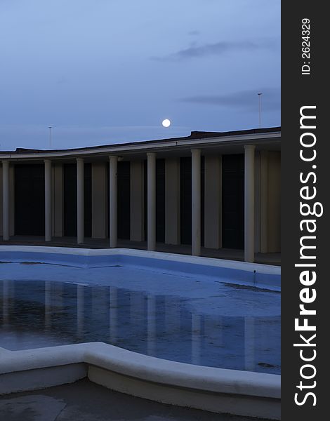 Early morning at Deauville bathouse of the moviestars. The swimming pool with just a bit of water in it and the moon above  the colonade. Early morning at Deauville bathouse of the moviestars. The swimming pool with just a bit of water in it and the moon above  the colonade.