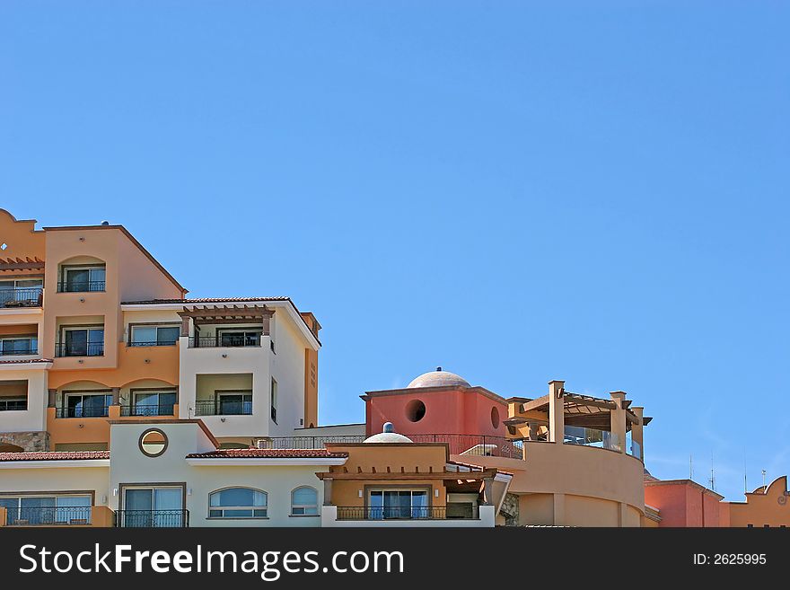 Multi colored condos on a hill against blue sky. Multi colored condos on a hill against blue sky