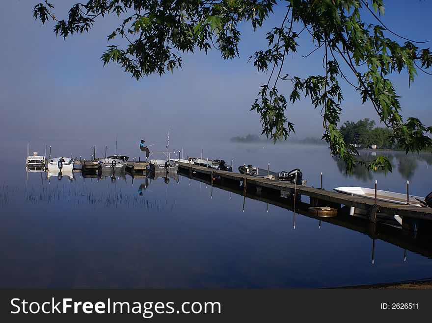 Early morning lake side, a pier with docking fishing boats